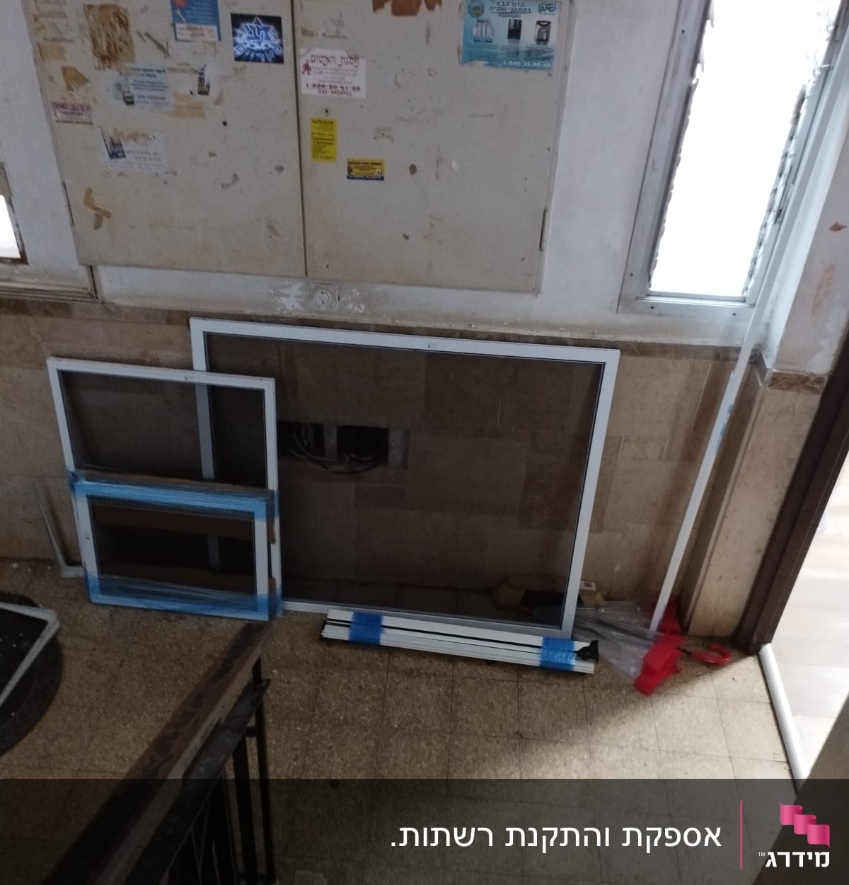 מסגרות אלומיניום מונחות על הרצפה ליד קיר